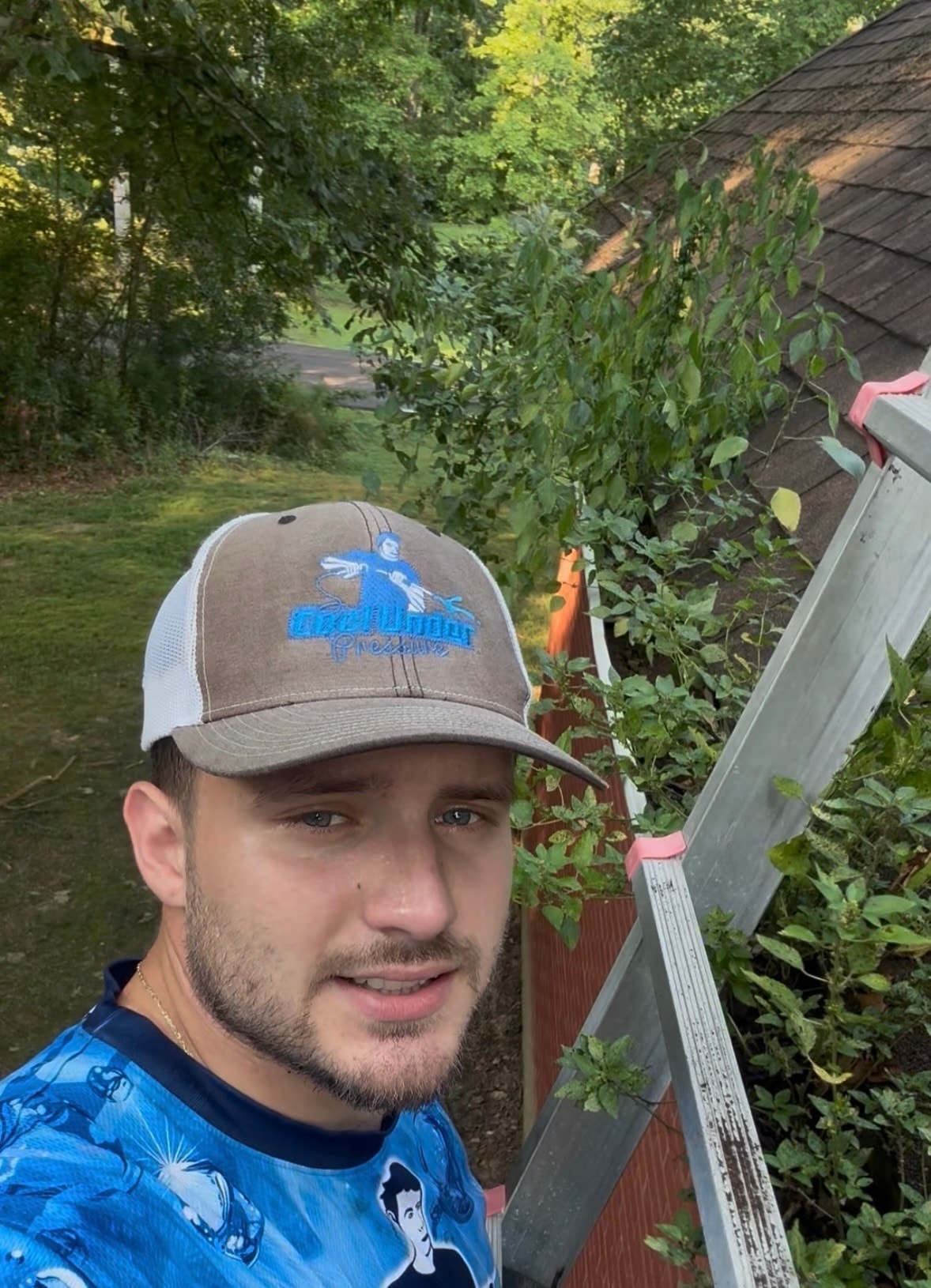 Cool Under Pressure technician on a ladder at a gutter cleaning job — gutters packed with debris